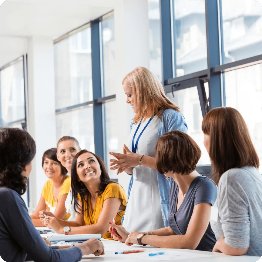 Formadora conversando con un grupo de alumnas adultas en un aula luminosa